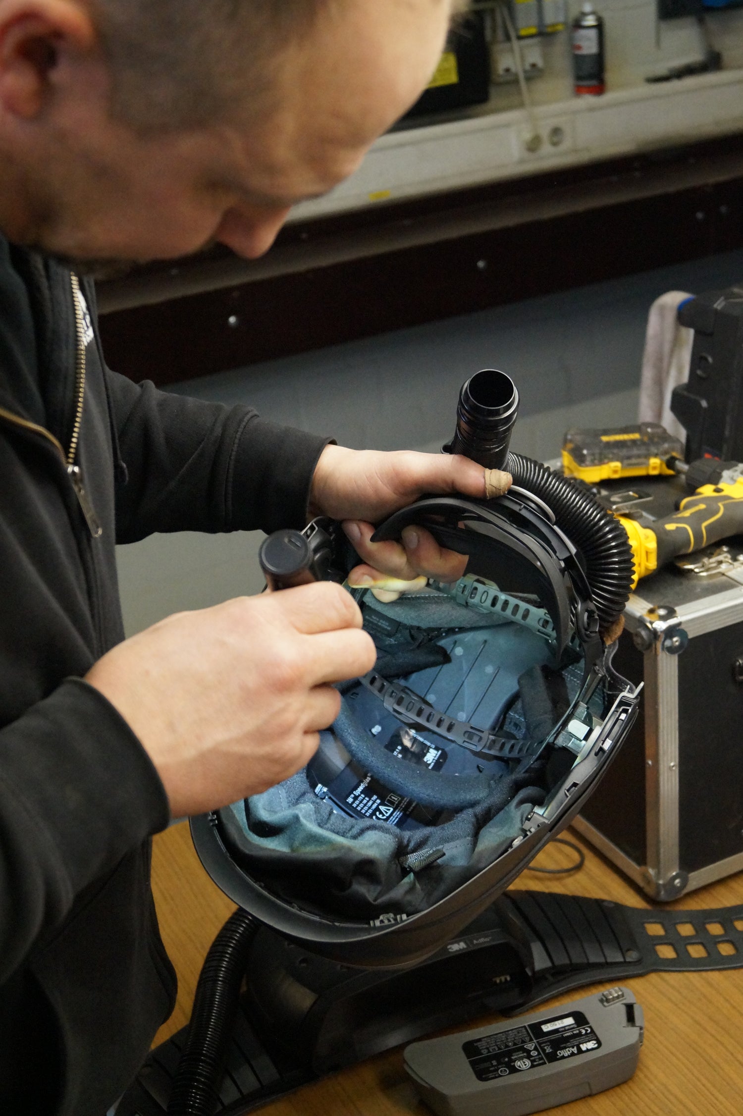 Techniker der Kaack GmbH führt präzise Wartungs- und Reparaturarbeiten an Schweißhelmen mit Frischlufteinheit durch, um optimale Sicherheit und Komfort für den Nutzer zu gewährleisten.